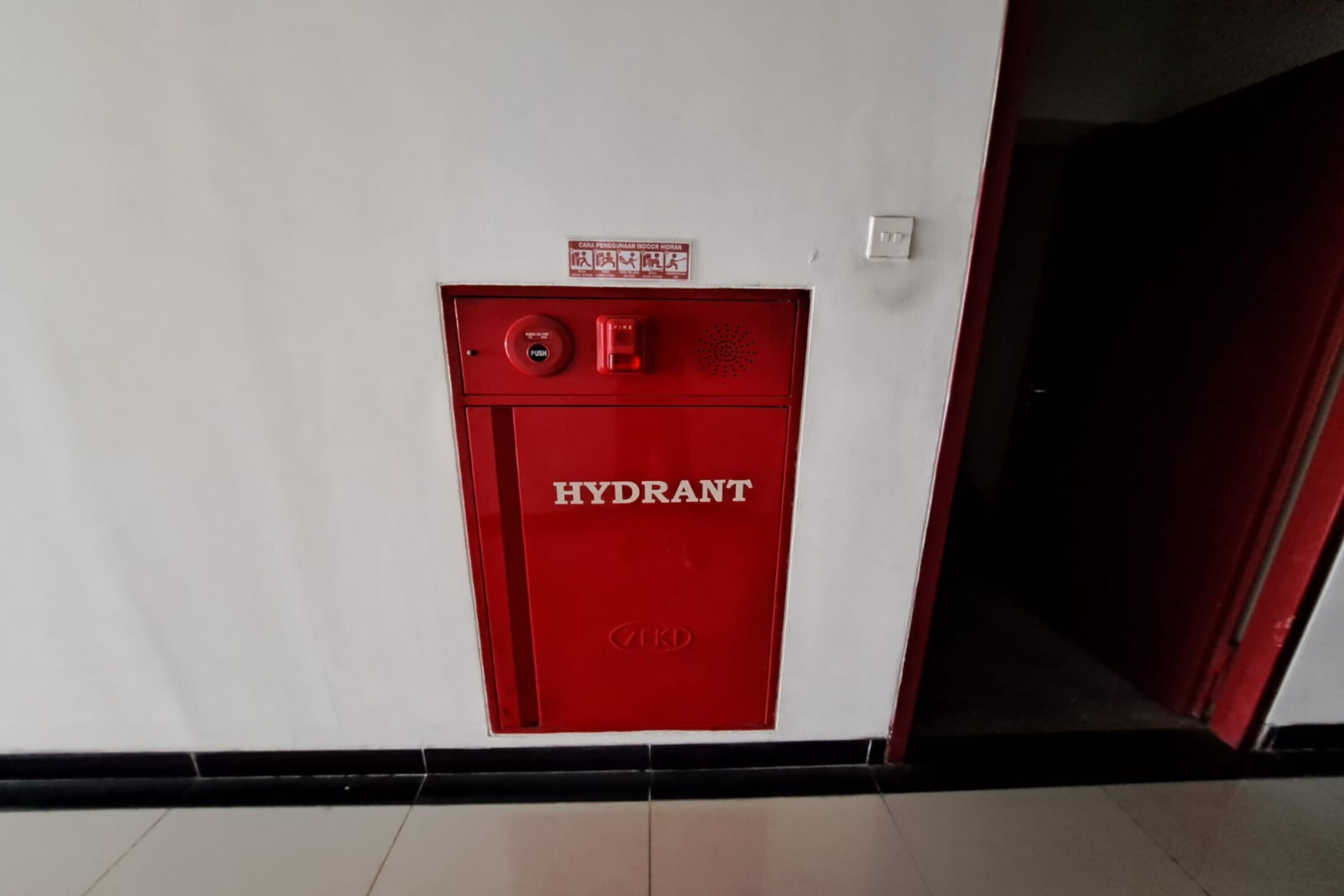 A red hydrant with the label "HYDRANT" on a white wall.