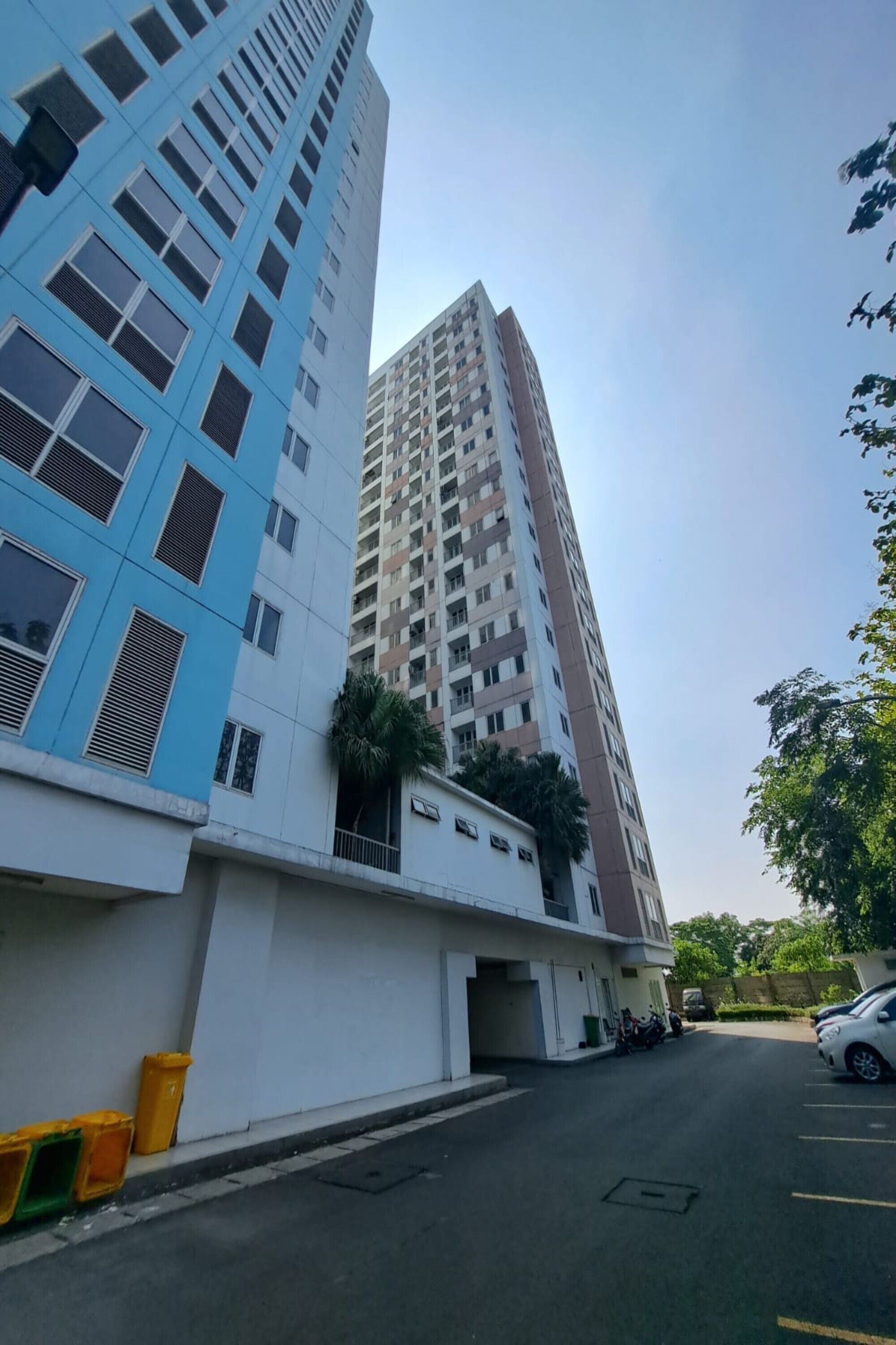 Un moderno grattacielo con facciata blu e un edificio adiacente di colore bianco.