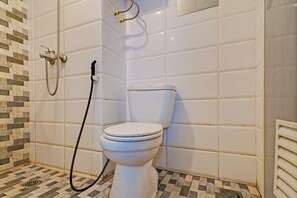 Een badkamer met een toilet, douche en betegelde vloer.