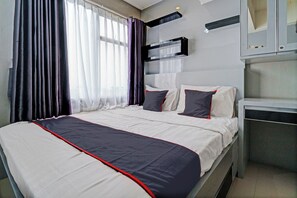 Een hotelkamer met een bed, gordijnen, een televisie en een bureau.