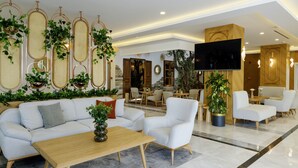 Un moderno vestíbulo de hotel con un sofá, sillones, una mesa de centro y un televisor montado en la pared.