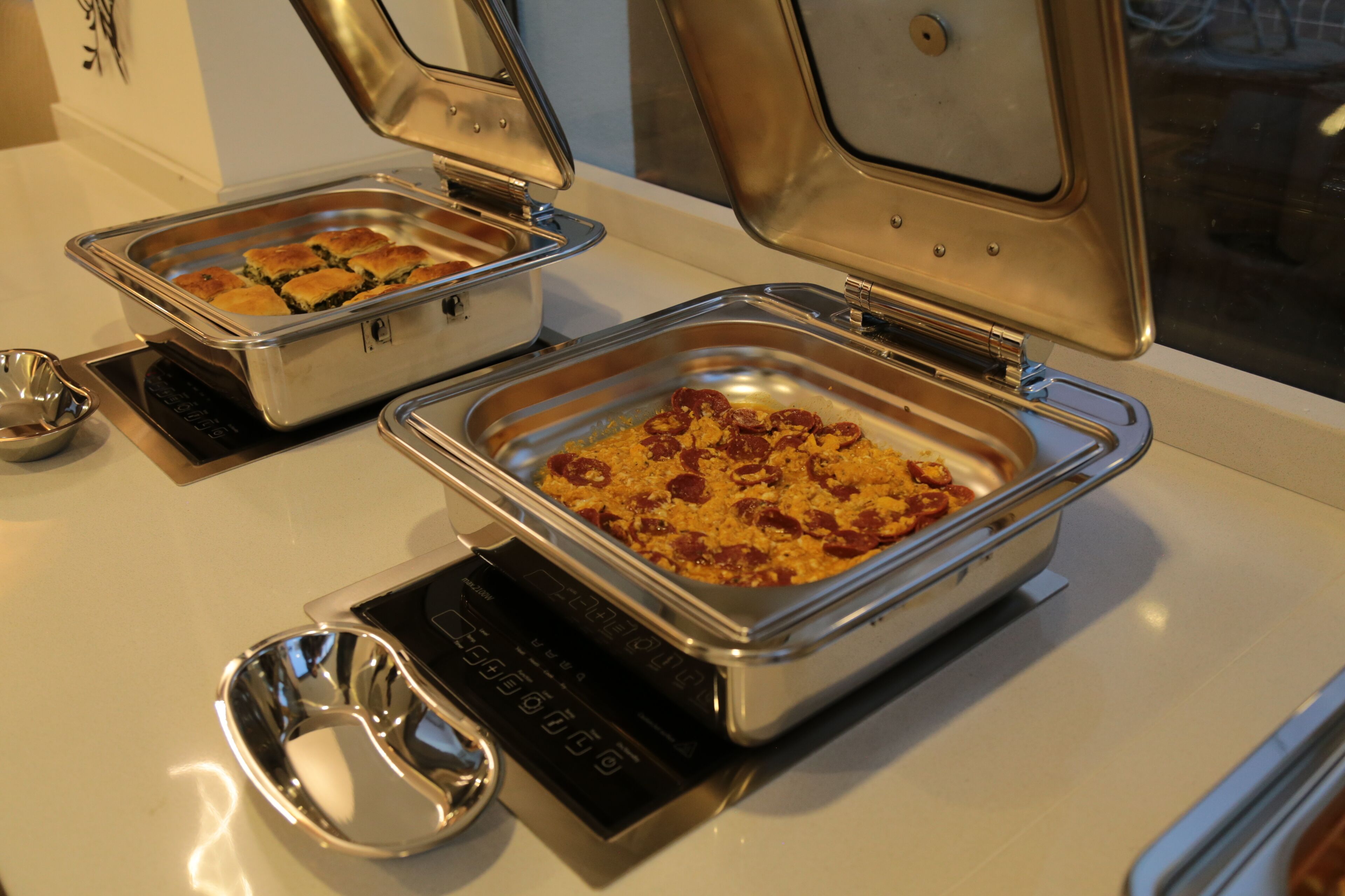 Una mesa de buffet con diversos platos en fuentes de metal.