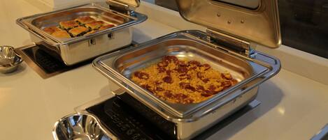 Una mesa de buffet con diversos platos en fuentes de metal.