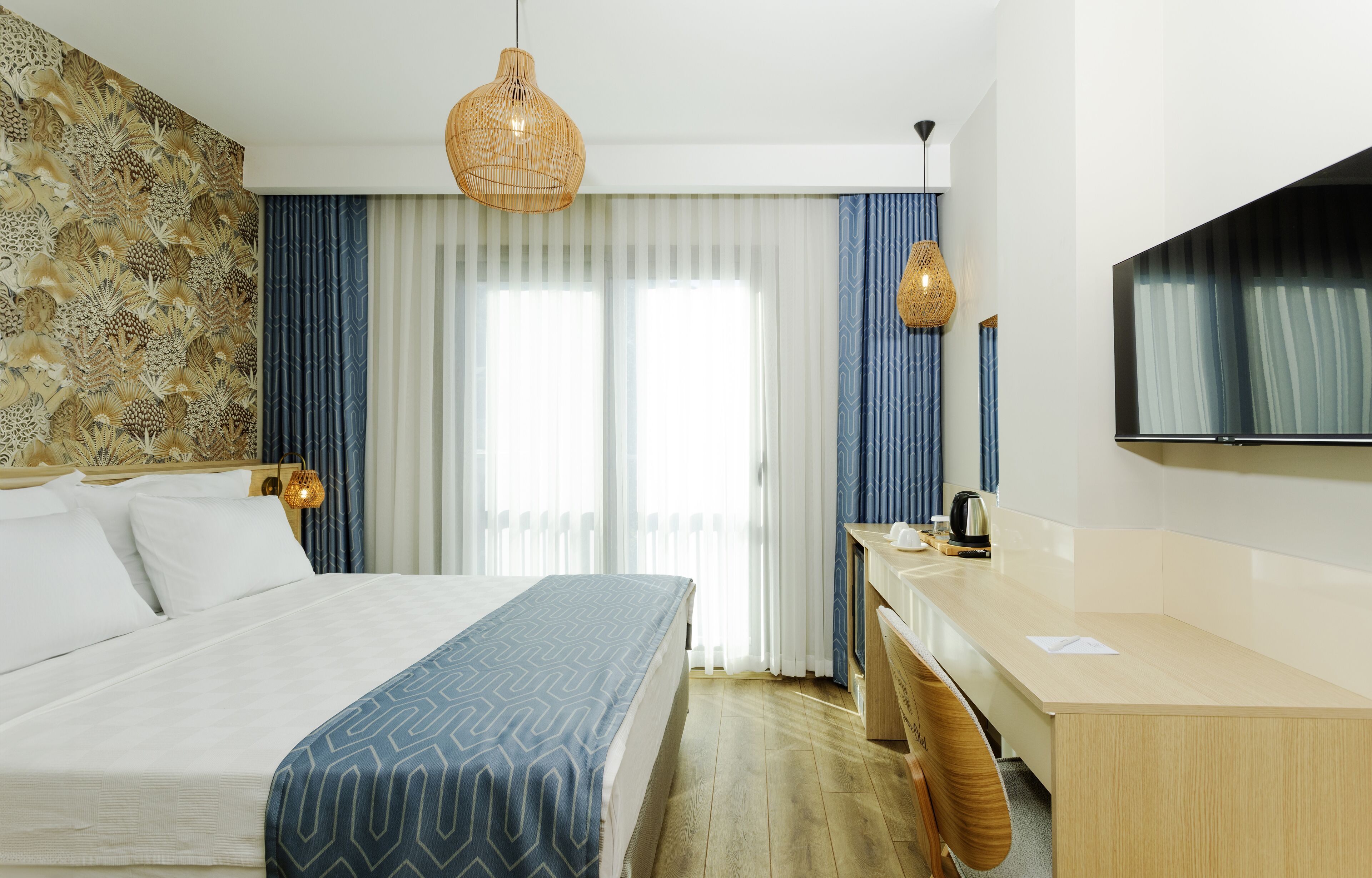 A hotel room with a large bed, a desk, and a television.