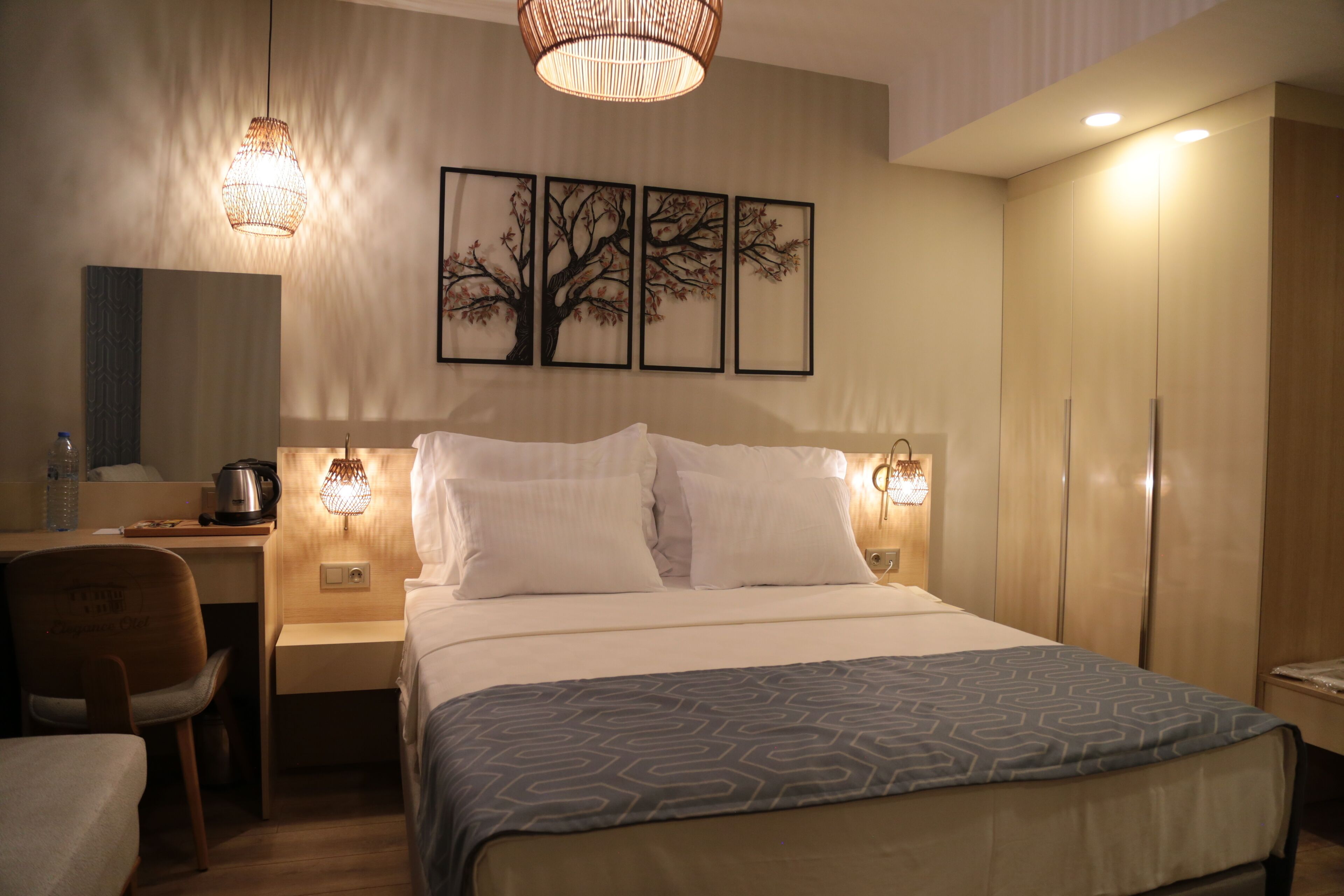 Una habitación de hotel con cama, mesitas de noche, escritorio, silla y armario.