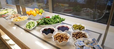Un bufé con diversos alimentos, incluyendo frutas, verduras y quesos.