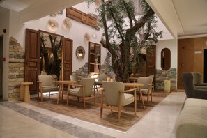 A cozy indoor seating area with wooden furniture, stone walls, and a large tree centerpiece. -  GULLUK UNO ELEGANCE OTEL (Milas)