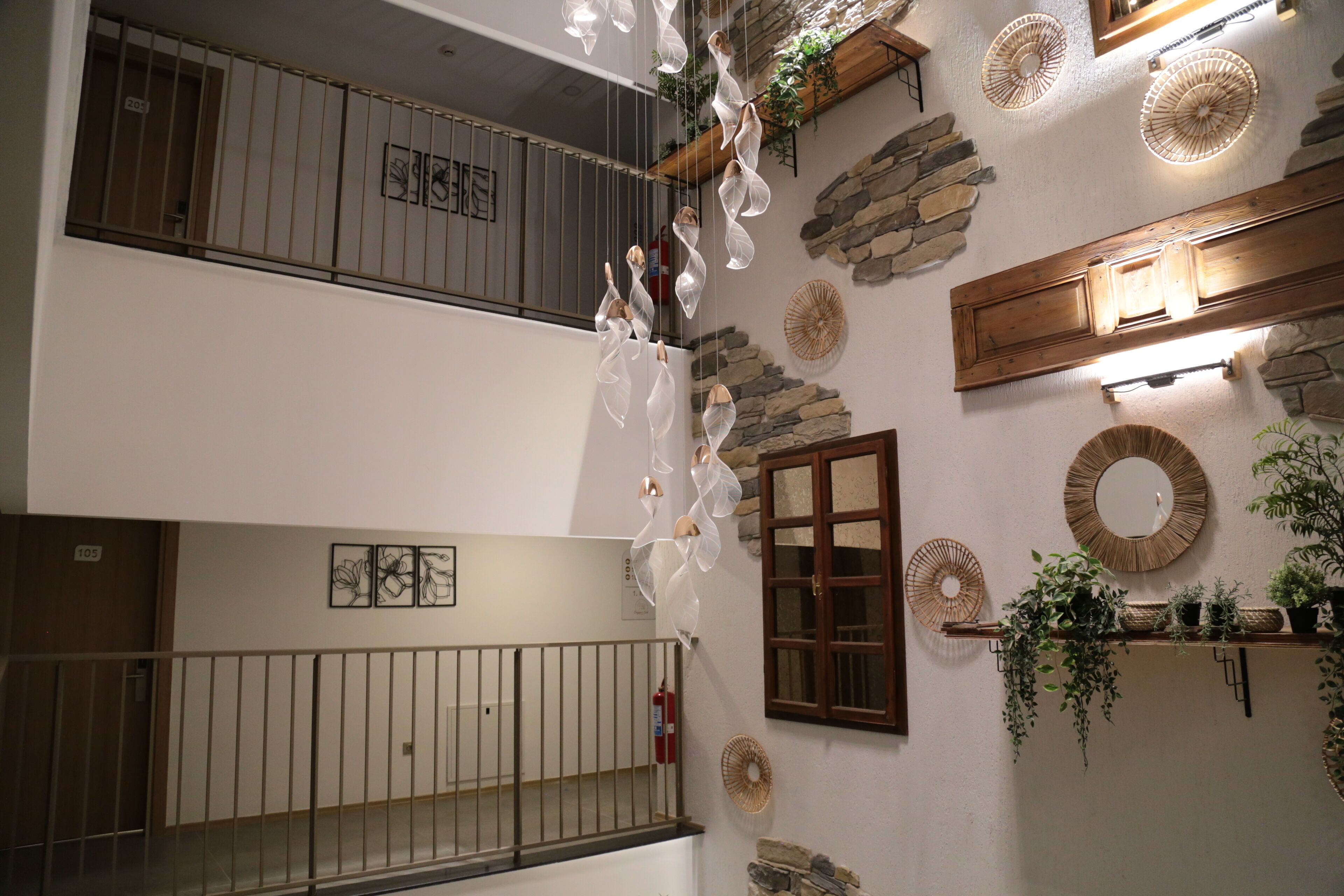 A multi-level interior with a staircase, decorative wall elements, and a wooden shelf with plants.