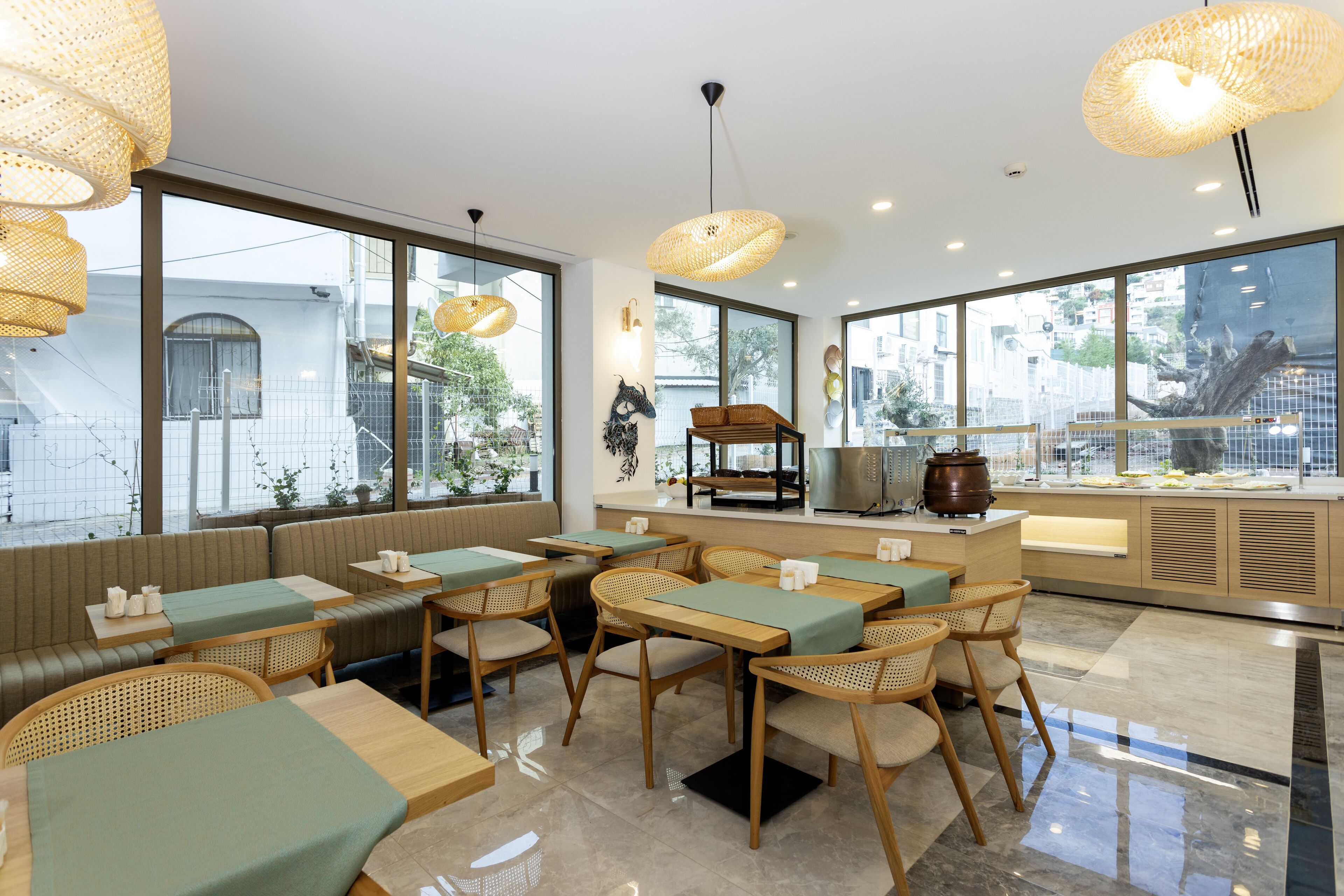Un restaurante moderno con ventanas amplias, sillas de mimbre y una barra central con una máquina de café.