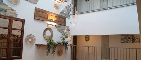 A multi-level interior with stone accents, wooden beams, and a balcony with metal railings.