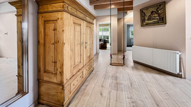 A hallway with wooden flooring, a large wooden cabinet, a radiator, and a framed picture on the wall. - Kamin Indoorschaukel Smart TV Bose Anlage Ferienhaus Kupferschmiede (Wernigerode)