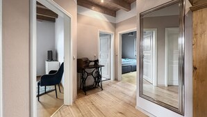 A hallway with wooden flooring, a sewing machine, a chair, and a bed in the background. - Kamin Indoorschaukel Smart TV Bose Anlage Ferienhaus Kupferschmiede (Wernigerode)