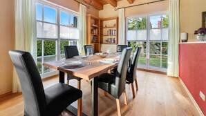 A dining area with a wooden table, black chairs, and a bookshelf. - Kamin Indoorschaukel Smart TV Bose Anlage Ferienhaus Kupferschmiede (Wernigerode)