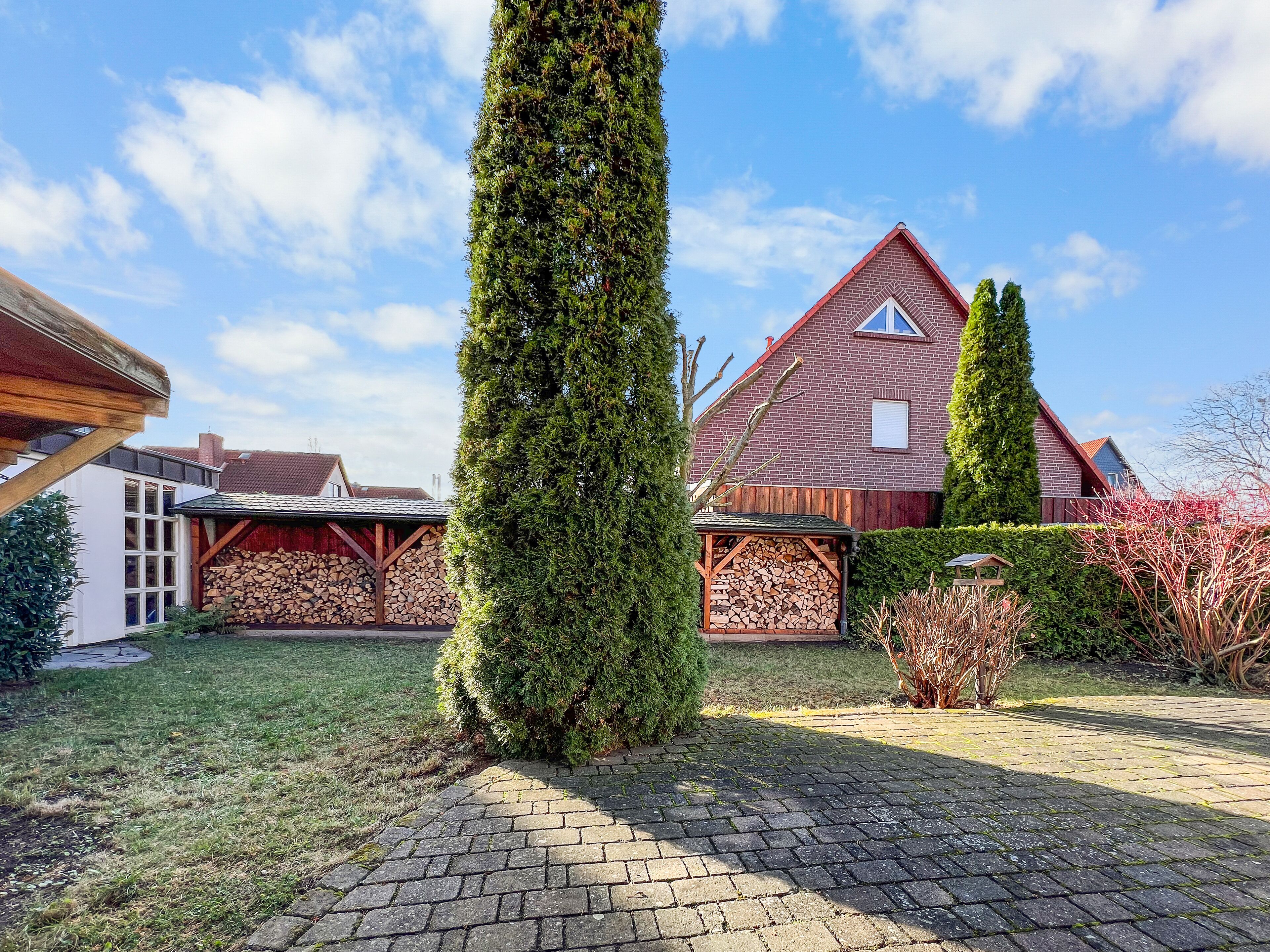A brick house with a sloped roof, a wooden fence, and a well-maintained lawn.