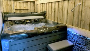 Un bain à remous avec un intérieur en bois, un banc et une rambarde en métal.