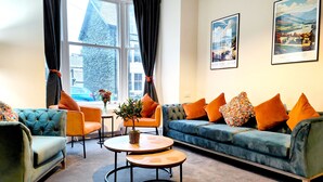 Un salon moderne avec un canapé bleu, des fauteuils orange et une table basse ronde.