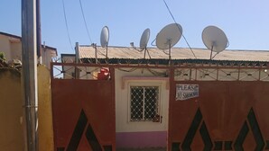 A gated entrance with a sign prohibiting smoking, a satellite dish on the roof, and a building with a window and door. - Beautiful 3-bed House in Serrekunda (Serrekunda)