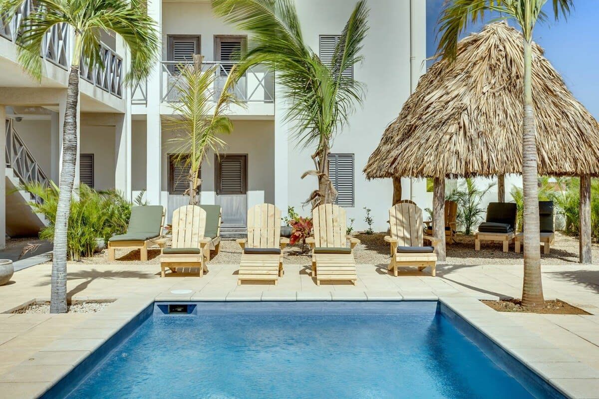 A pool area with lounge chairs and a thatched roof structure.