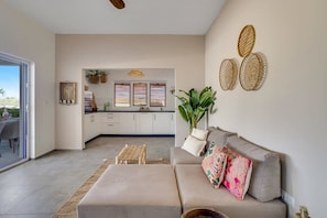 A modern living room with a sofa, a coffee table, and a dining area with a table and chairs.
