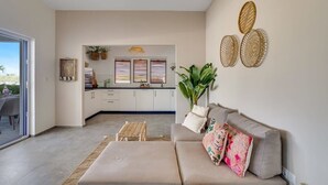 Un salon moderne avec un canapé, une table basse et un coin repas visible à travers une porte ouverte.