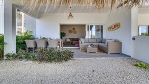 Un espace extérieur aménagé avec un toit de chaume, un canapé et une table à manger.
