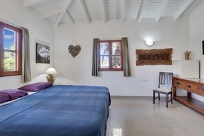 A bedroom with a bed, a desk, a chair, a window with curtains, and wall art. - Salinja Breeze (Kralendijk)