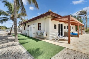 A single-story house with a covered patio, air conditioning units, and a small outdoor seating area. - Salinja Breeze with pool and salt lake view (Kralendijk)