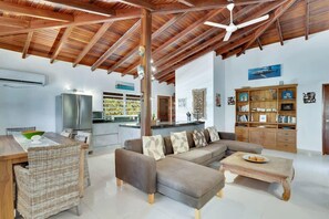 A spacious living area with a wooden ceiling, a sofa set, a dining table, and a kitchen in the background. - Salinja Breeze (Kralendijk)