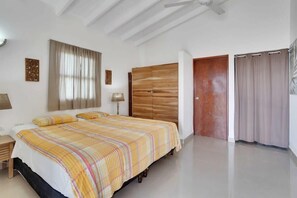 A bedroom with a bed, a wooden wardrobe, a door, and a window with curtains. - Salinja Breeze (Kralendijk)