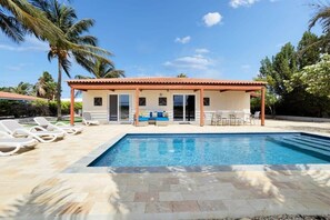 A poolside area with a pool, lounge chairs, and a building with a red roof. - Salinja Breeze with pool and salt lake view (Kralendijk)