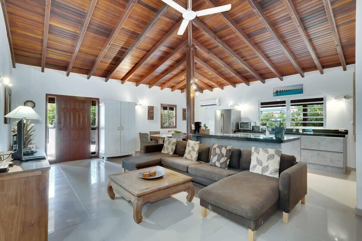 A spacious living area with a high ceiling, a central ceiling fan, and a kitchen area with a modern design.