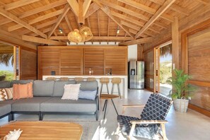 A modern interior with a wooden ceiling, a sofa, a dining area, and a kitchen.
