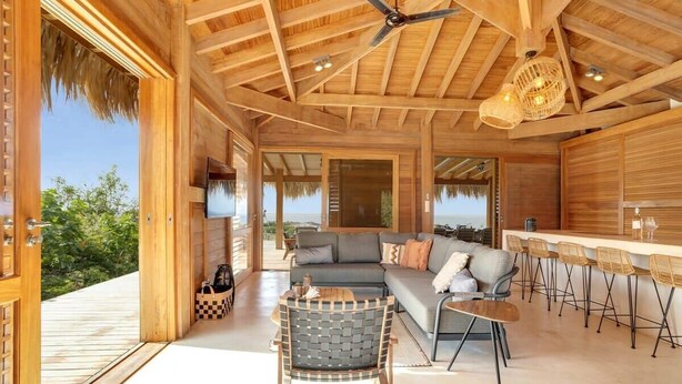 A spacious living area with a wooden ceiling, a sofa set, a dining table with chairs, and a bar area. - Kas Berde with a large private pool and spectacular view towards Klein Bonaire (Kralendijk)