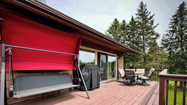 Una terraza techada con una parrilla, mobiliario exterior y una puerta corrediza que da a un patio cubierto.