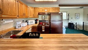 Una cocina con armarios de madera, microondas, estufa y refrigerador.