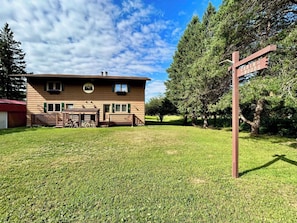 Uma cabana com fachada de madeira, um deck e uma placa indicando 'Cabin in the Woods'.