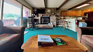 Una sala de estar acogedora con chimenea, muebles de madera y vistas amplias por las ventanas.