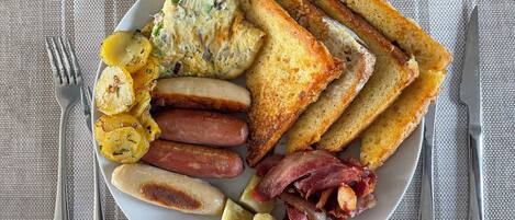 A plate of breakfast food including toast, sausages, bacon, and potatoes.