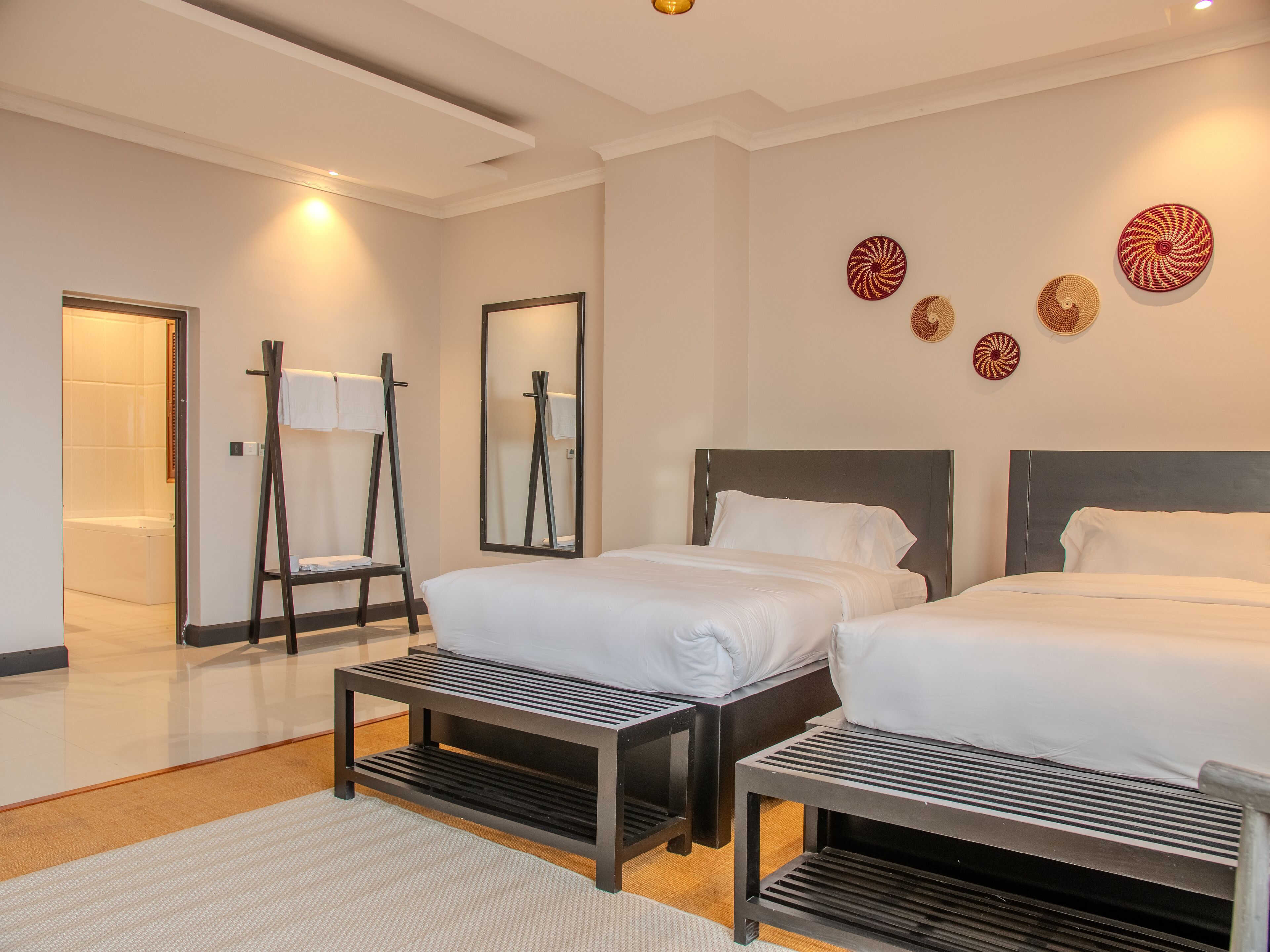 Une chambre d’hôtel moderne avec deux lits, un grand miroir et des œuvres d’art décoratives au mur.
