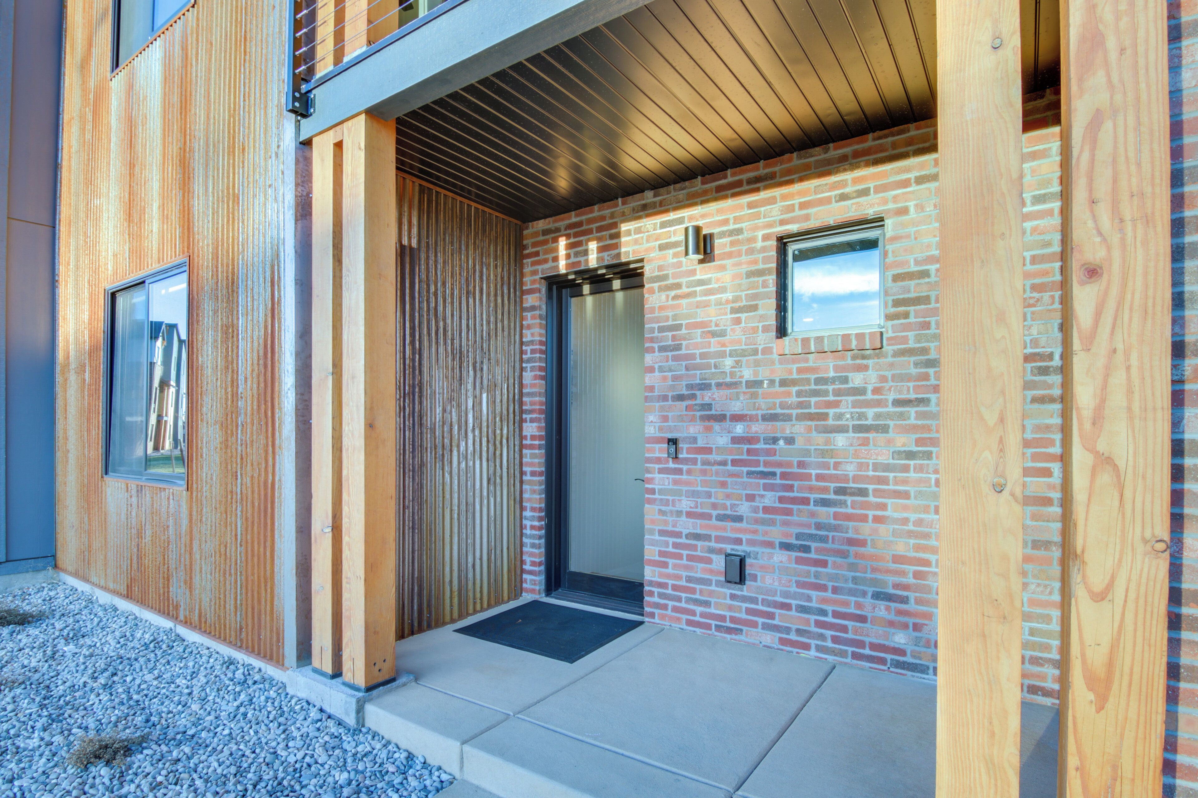 A modern building with a wooden facade, a brick wall, and a metal-framed elevator.