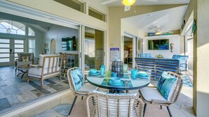 A spacious outdoor patio with wicker furniture, a glass table, and a ceiling fan. - Gorgeous Punta Gorda Home w/ Lanai & Private Pool! (Punta Gorda)