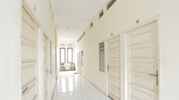 A corridor with white doors, numbered 30 and 31, leading to a room with a window. - Hotel O Guest House Sae Madani (Sepaku)