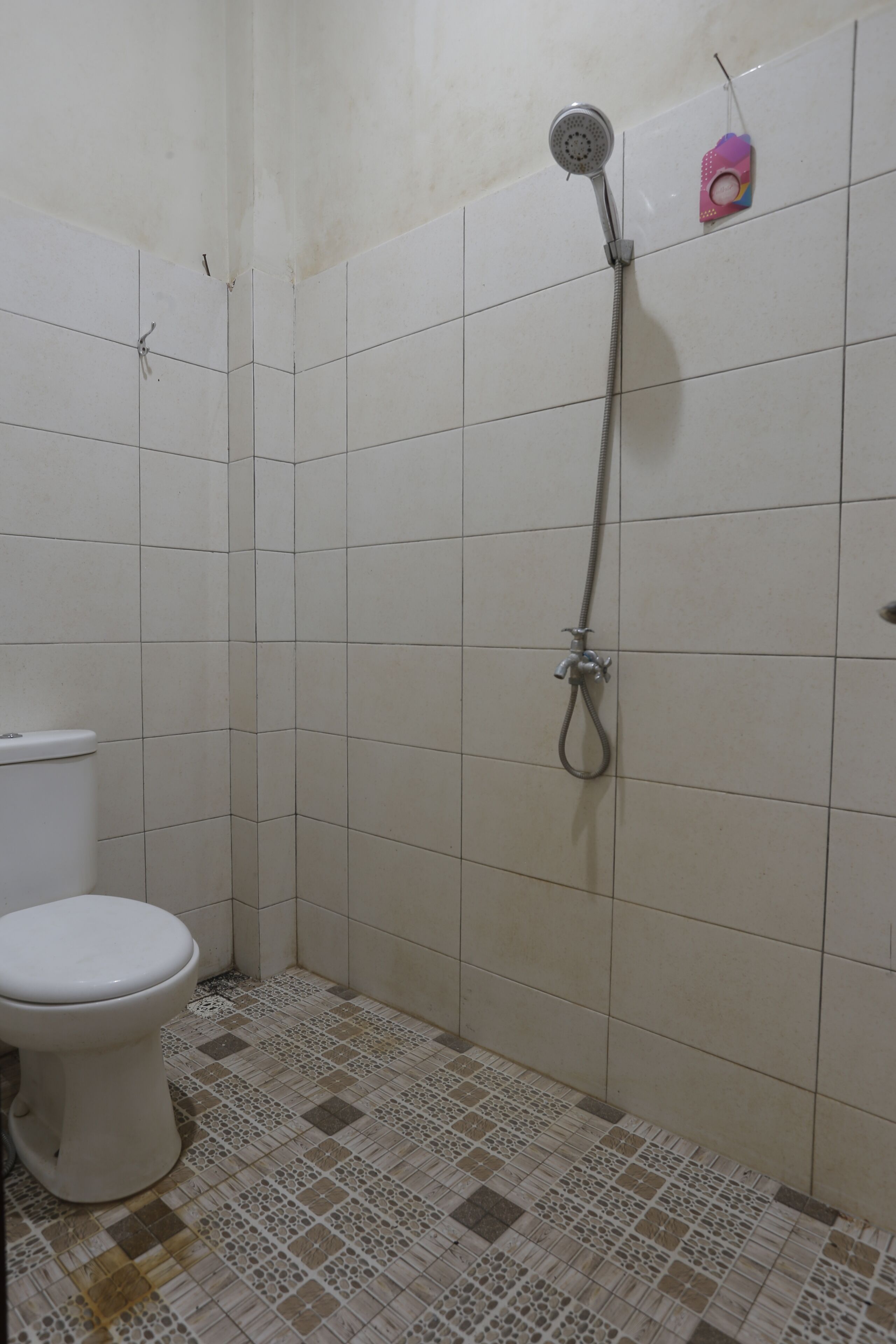 A small bathroom with a toilet, a shower, and tiled walls.