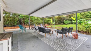 An outdoor patio with a covered seating area, a table, and chairs.
