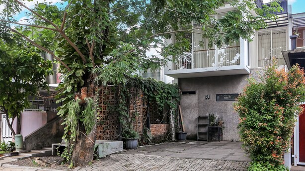 A residential building with a brick wall, a tree, and potted plants. - OYO 93370 Lot Thirty Six (Bekasi)