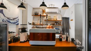A coffee shop counter with a coffee machine, shelves with bottles, and a mural on the wall. - OYO 93370 Lot Thirty Six (Bekasi)