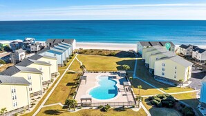 Un resort con piscina central, propiedades frente a la playa y vista despejada al océano.