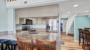 Una cocina moderna con encimeras de granito, electrodomésticos de acero inoxidable y sillas de madera.