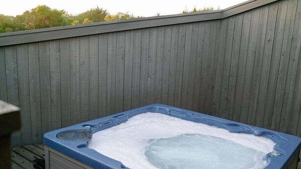 A hot tub with a control panel, surrounded by a wooden fence. - Oasis | Ocean Views & Private Hot Tub (Sea Ranch)