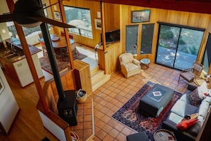 Ein großzügiger Wohnbereich mit Kamin, Fernseher und einem großen Fenster mit Blick auf eine Terrasse.
